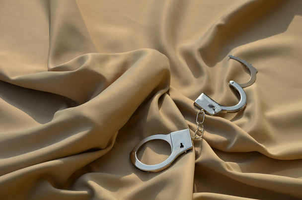 male cock under a satin sheet in bed. it is a gift for a partner bought in a sex shop. the picker or dildo is tastefully arranged with police handcuffs for play in the bedroom bed - Photo, image