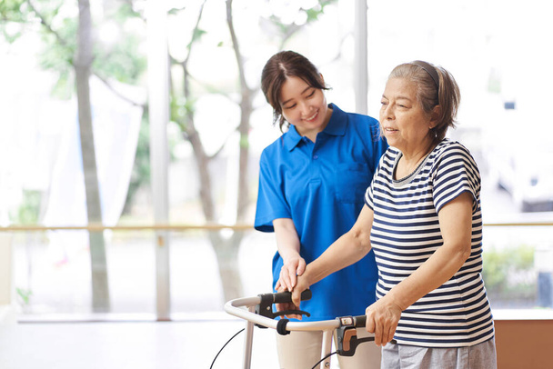 A caregiver who assists the elderly walking with a walker - Photo, Image