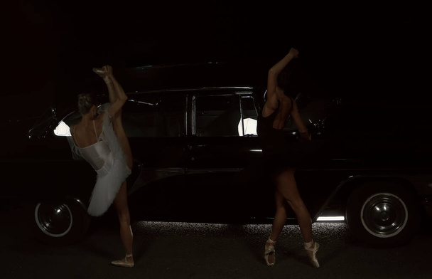 Portrait of two ballet dancers dancing at night near retro car.  - Foto, Imagen
