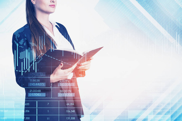 Businesswoman wearing formal suit is holding notebook in her hands. Financial chart and graph in the foreground. City skyscrapers in the background. Concept of successful trading on stock market - Foto, Imagem