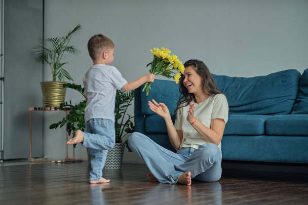 Happy mother day. child son congratulates mother on holiday and gives flowers. congratulating her on mothers day during holiday celebration at home - Fotoğraf, Görsel