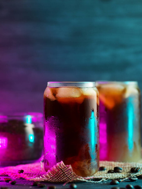 cold brew cold coffee in tall glasses with cream and roasted coffee beans. neon style backlight background - Foto, immagini