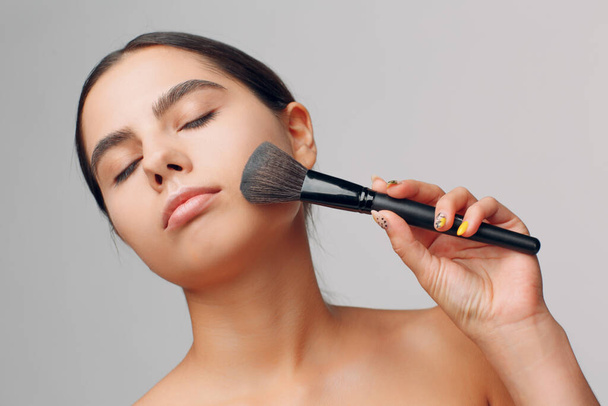 Portrait of young beautiful positive woman with nude make up and brush. - Foto, Bild