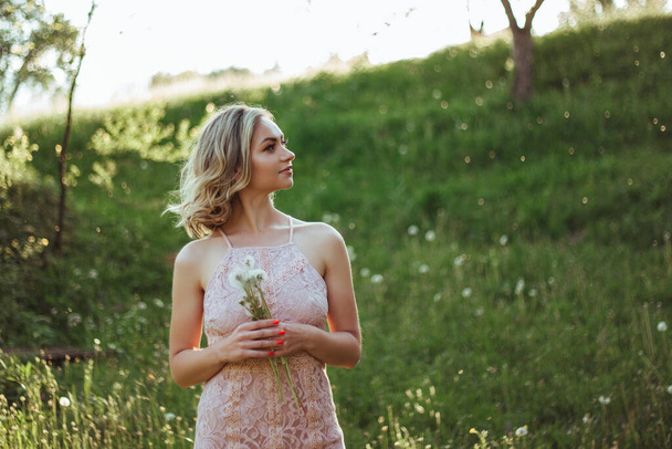 a woman at sunset in a field of dandelions in a pink dress . the concept is not allergic . - Photo, Image