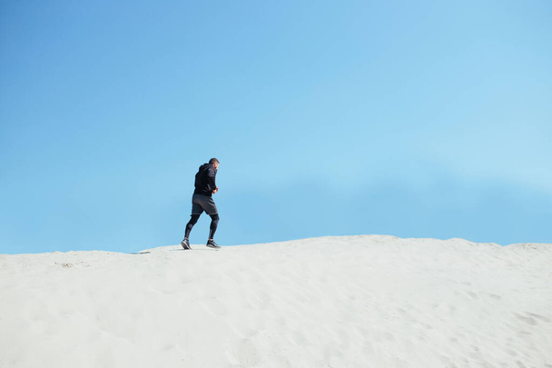 male athlete climb the sandy mountain. - Photo, image