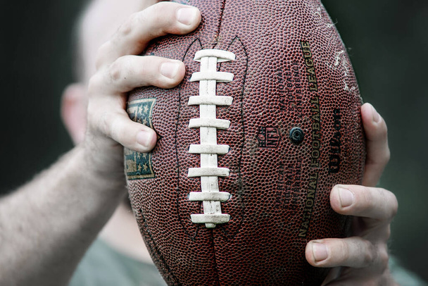  Um atleta profissional detém uma bola para o futebol americano. - Foto, Imagem