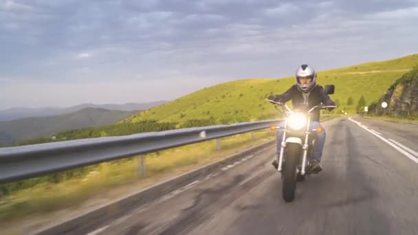 Tiro frontal de motociclista con casco abierto a caballo de la motocicleta en asfalto carretera con Rural - Metraje, vídeo