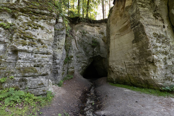 Naturobjekt. Weiße Felsen mit einer tiefschwarzen Höhle, aus der eiskaltes, steifes Wasser fließt. Es gibt magische Legenden über diesen Ort, da in der Antike Menschen in der Höhle verschwanden und nicht gefunden wurden. - Foto, Bild