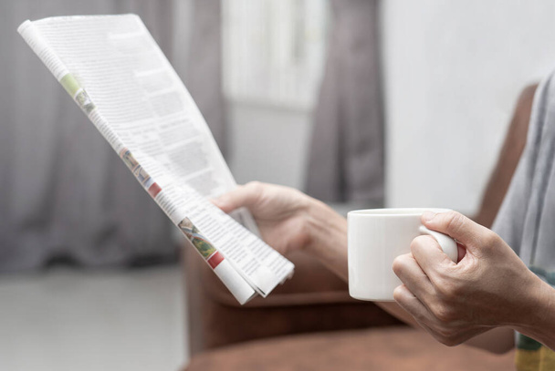 Women drinking coffee and looking news paper in home search news and job announce  - Foto, Imagem