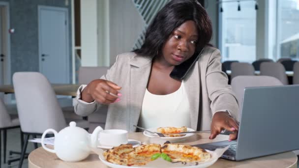 Mulher negra ocupada com telefone e laptop almoçando no café - Filmagem, Vídeo