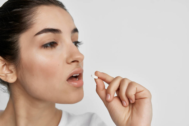 женщина кладет таблетку в рот лекарства для здоровья крупным планом - Фото, изображение
