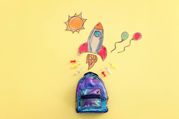 Back to school concept. Top view image of bag and space ship over pastel yellow background - Foto, Imagen