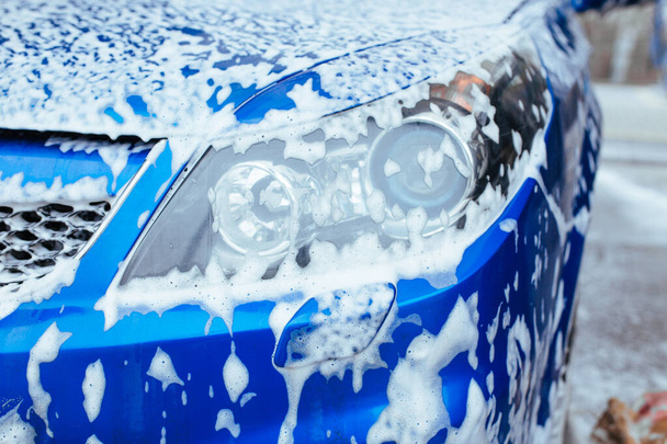 el faro delantero del coche está cubierto de espuma de jabón. auto-servicio de lavado de coches - Foto, imagen