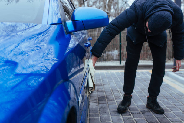 Ένας άνδρας με ένα κουρέλι να στεγνώσει το αυτοκίνητο. έννοια πλυντήριο αυτοκινήτων - Φωτογραφία, εικόνα