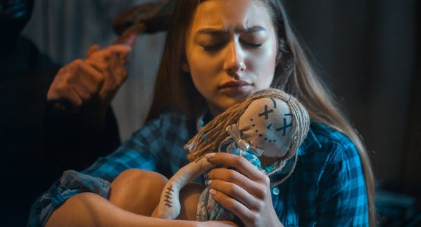 a frightened girl embraces a toy and a maniac is behind her . concept - Photo, Image