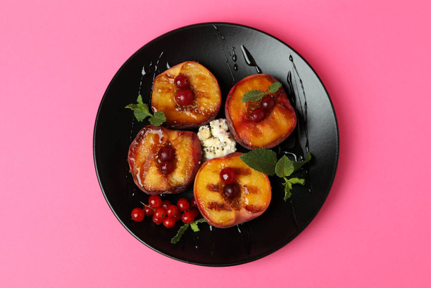 Plate with tasty grilled peach on pink background - Foto, afbeelding