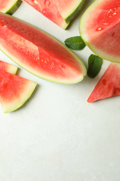 Watermelon slices and mint leaves on white textured table - 写真・画像