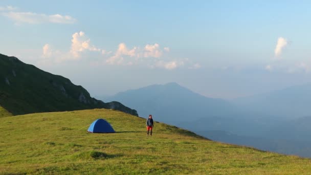 Hiker goes from the tent to the high mountain in summer - Footage, Video