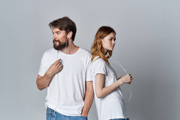 junges Paar mit Kopfhörern, das gemeinsam Musik auf hellem Hintergrund hört - Foto, Bild