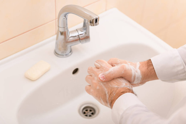 Händewaschen mit Seife oder Gel unter fließendem Wasser im Waschbecken, Sauberkeit und Hygiene, Männerhände in weißem Hemd - Foto, Bild