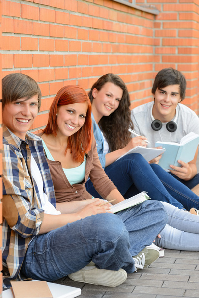 College students sitting outside by brick wall - Φωτογραφία, εικόνα