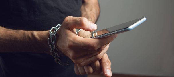 a man in chains holding a phone - Фото, зображення