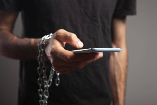 a man in chains holding a phone - Foto, afbeelding