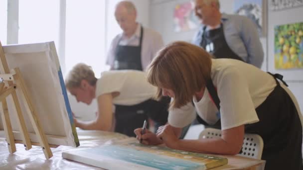 Χαρούμενη ομάδα ηλικιωμένων ζωγραφίζουν μαζί εικόνες στην τάξη. - Πλάνα, βίντεο