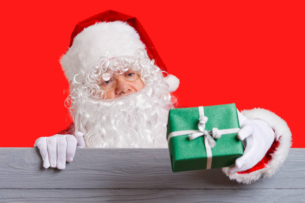 Санта Клаус держит в руке зеленую коробку подарков. Концепция продажи Рождества - Фото, изображение
