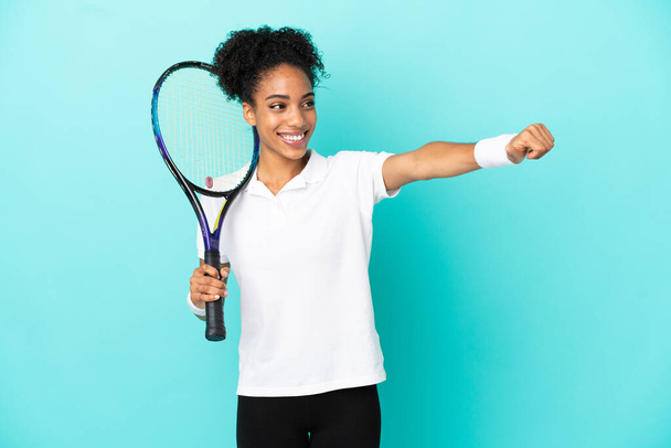 Joven jugadora de tenis aislada sobre fondo azul dando un gesto de pulgares hacia arriba - Foto, imagen