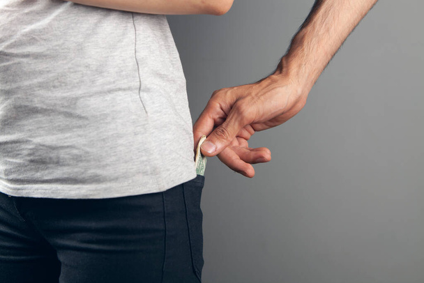 un hombre roba dinero del bolsillo trasero de una mujer - Foto, Imagen