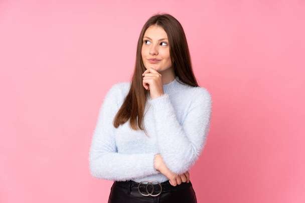 Teenager caucasian girl isolated on pink background and looking up - Foto, imagen