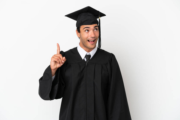 Jeune diplômé universitaire sur fond blanc isolé dans l'intention de réaliser la solution tout en levant le doigt - Photo, image