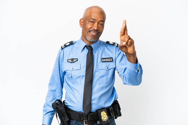 Νεαρός αστυνομικός απομονωμένος σε λευκό φόντο με τα δάχτυλα σταυρωμένα και ευχόμενος το καλύτερο - Φωτογραφία, εικόνα