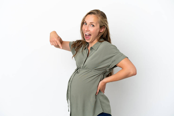 Νεαρή καυκάσια γυναίκα απομονωμένη σε λευκό φόντο έγκυος και δείχνοντας προς την κοιλιά - Φωτογραφία, εικόνα