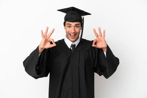 Nuori yliopisto valmistunut yli eristetty valkoinen tausta osoittaa ok merkki sormilla - Valokuva, kuva