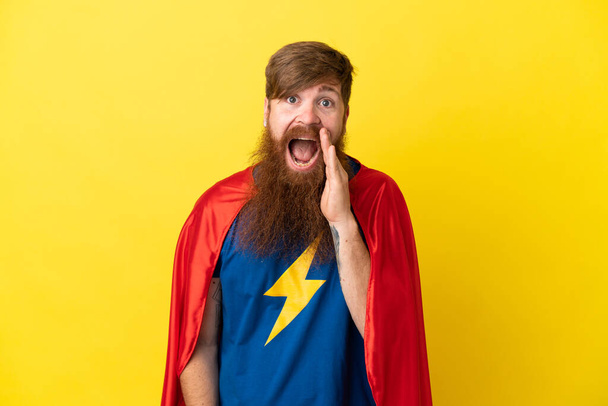Redhead Super Hero man isolated on yellow background with surprise and shocked facial expression - Photo, Image