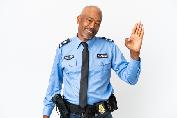 Jeune policier isolé sur fond blanc saluant à la main avec expression heureuse - Photo, image