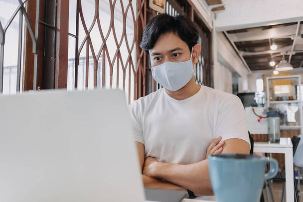 Man work in cafe with mask on the face. Concept of freelance with Covid. - Foto, Imagen