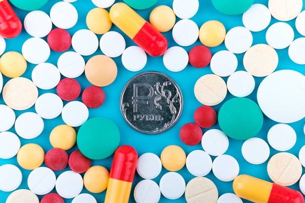 a moeda de rublo russa metálica rodeia-se de medicamentos de cores diferentes. um monte de drogas, pouco dinheiro - Foto, Imagem