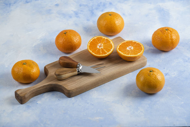 Close up photo of mandarins and wooden cutting board. High quality photo - Foto, afbeelding