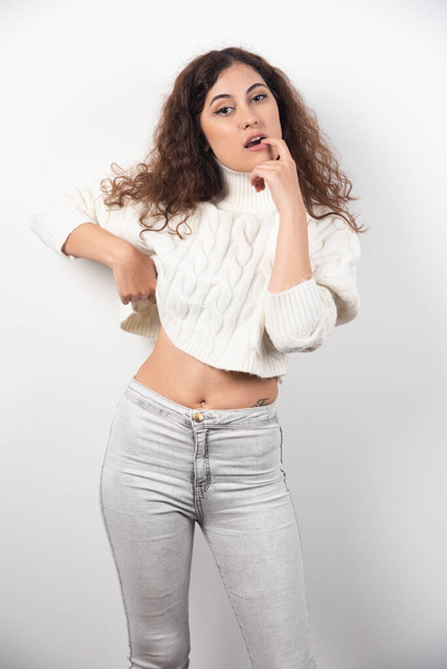 Young woman in white sweater standing over a white wall. High quality photo - Photo, Image