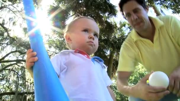 szczęśliwy chłopiec gra zabawka bat na trawie w parku - Materiał filmowy, wideo