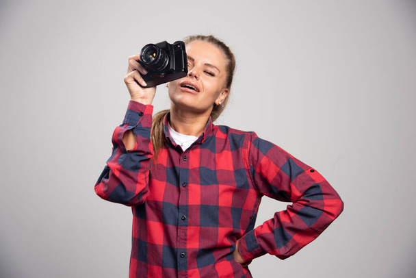 Fotografía rubia en camisa a cuadros toma fotos como un profesional. Foto de alta calidad - Foto, imagen
