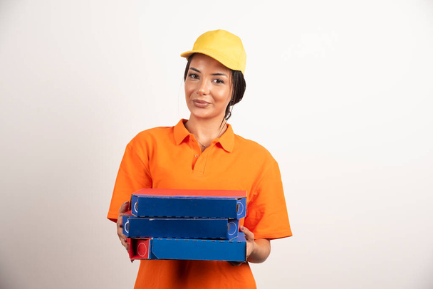 Молодая курьерша держит коробки с пиццей на белом фоне. Высокое качество фото - Фото, изображение