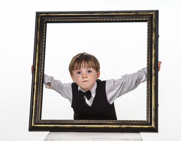 Freckled red-hair little boy with big picture frame. - Foto, Bild