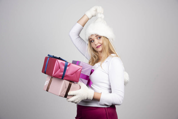 Schöne Frau mit Weihnachtsgeschenken auf grauem Hintergrund. Hochwertiges Foto - Foto, Bild