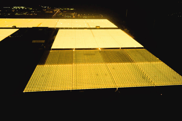 Теплица светится ярко-желтым по ночам, аэрофотосъемка - Фото, изображение