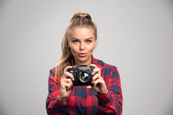 Blonde photograph in checked shirt taking photos and feels positive. High quality photo - Fotografie, Obrázek