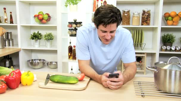 Καυκάσιος αρσενικό χρησιμοποιώντας ασύρματη έξυπνο τηλέφωνο στο σπίτι κουζίνα - Πλάνα, βίντεο